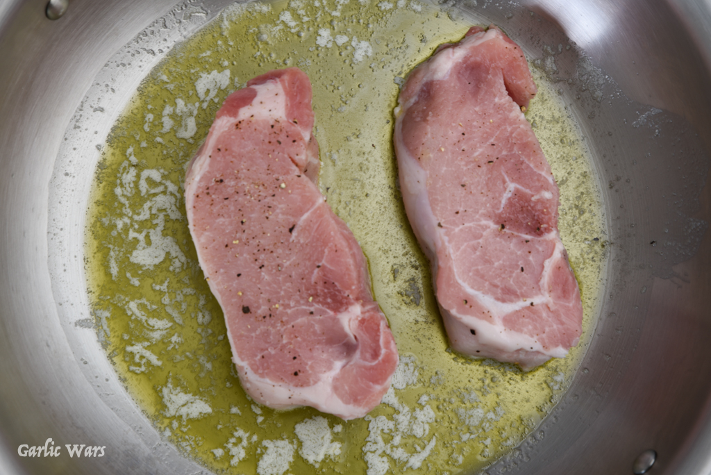 pork chops cooking in pan with butter and oil
