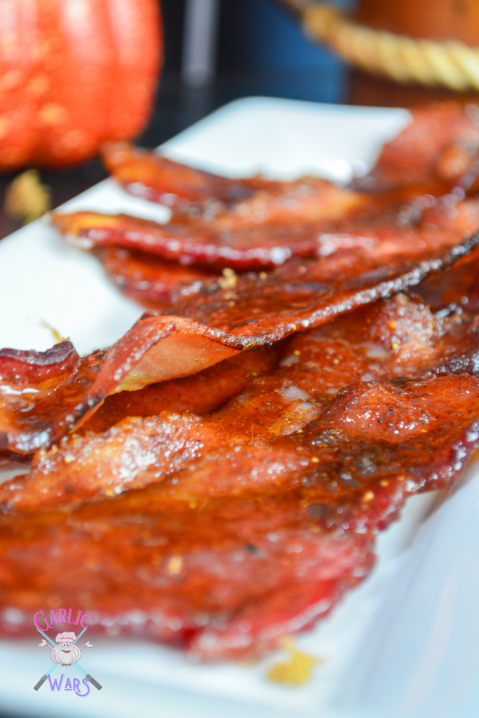 A close up of candied bacon on a long white plate.