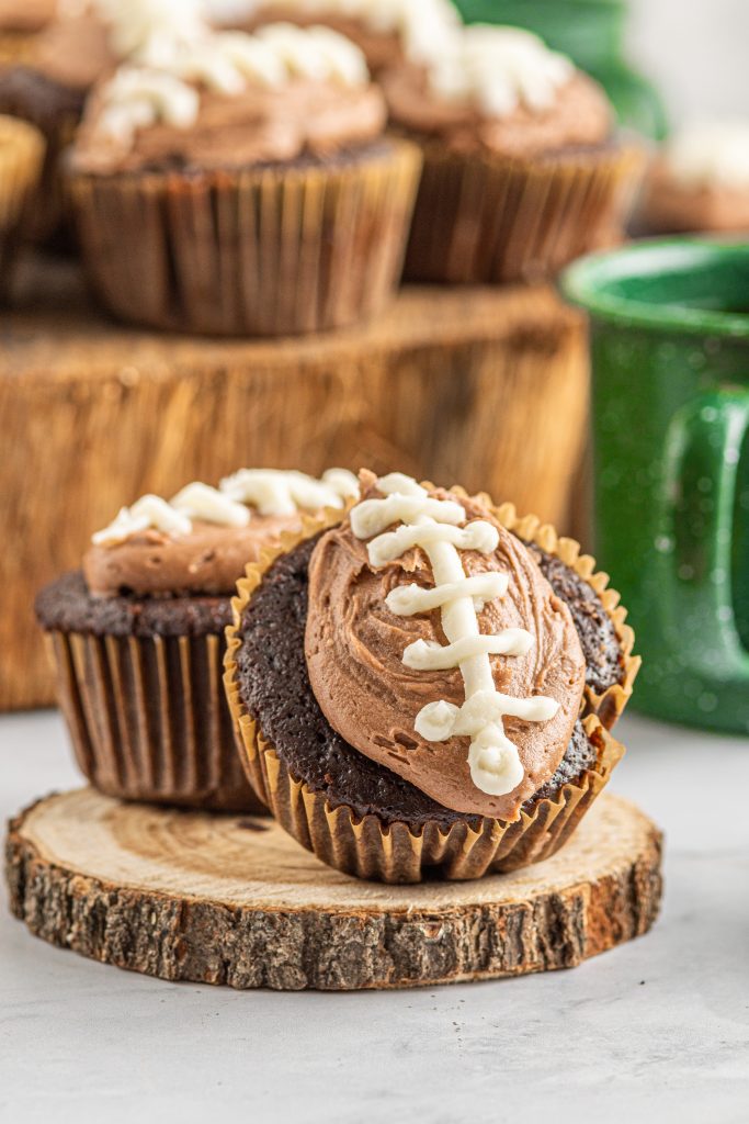 one cupcake tipped against another with a football design