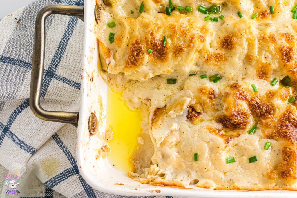 scalloped potatoes in a casserole pan with a scoop taken out