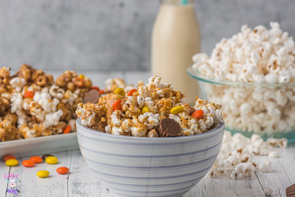 bowl of peanut butter popcorn with more popcorn and a glass of milk in the background