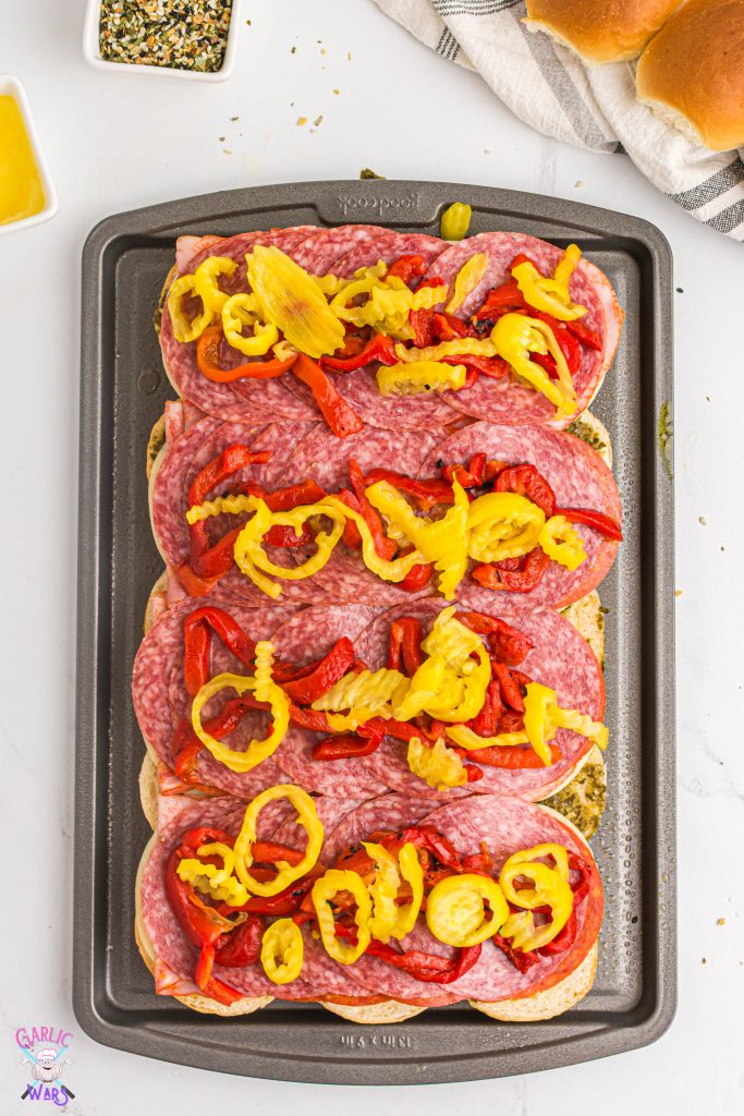 roasted red peppers and banana peppers on top of meats and cheese