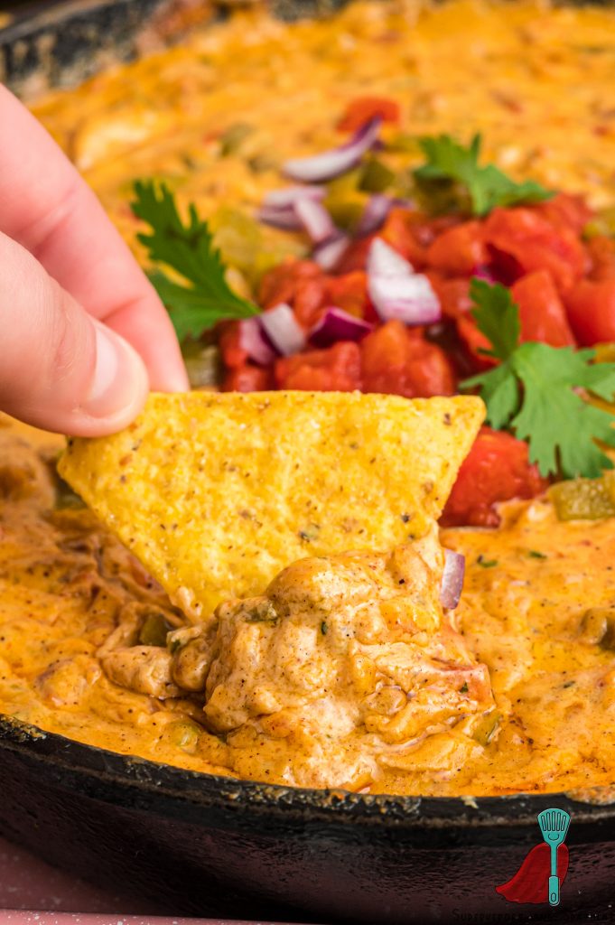 dipping a tortilla chip into queso dip