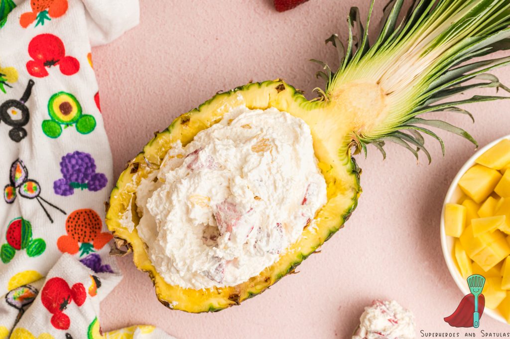 cheesecake salad in a pineapple bowl on a pink board