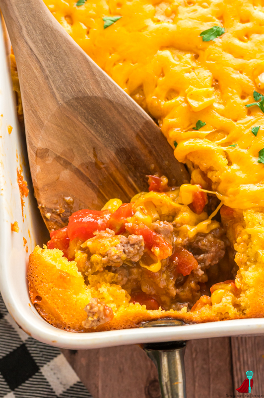 serving spoon in casserole to show ground beef filling and melty cheese